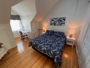 A bedroom with a bed, desk and chair.