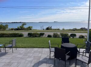 A patio with chairs and tables overlooking the water.