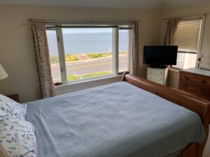 A bed room with a white bedspread and a tv