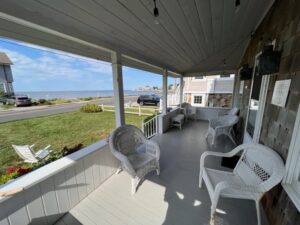 A porch with chairs and tables overlooking the ocean.