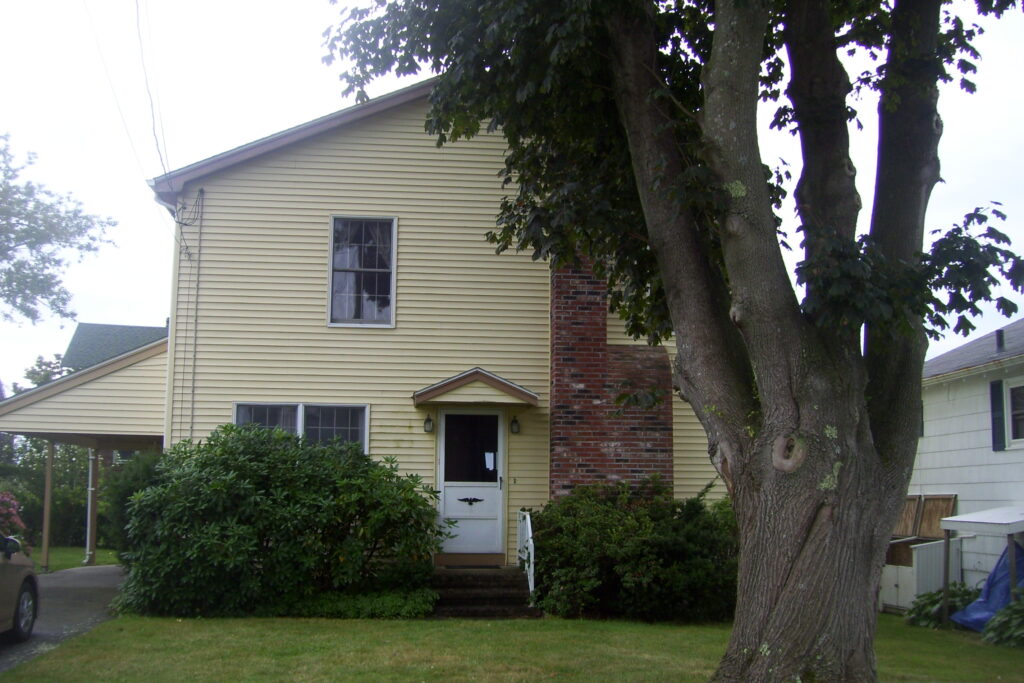 A yellow house with a tree in front of it.