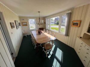 A dining room table with chairs and windows.