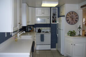 A kitchen with white cabinets and blue walls.