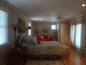 A bedroom with a bed, dresser and couch.