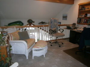 A living room with a couch, chair and desk.