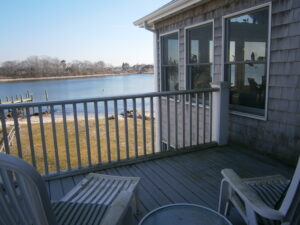 A deck with chairs and tables overlooking the water.