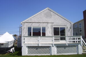 A white house with a porch and lattice on the side.