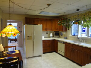 A kitchen with a table and chairs, refrigerator, microwave, oven, sink, and cabinets.