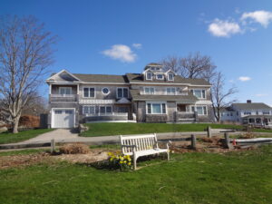 A bench in front of a house with a sky background