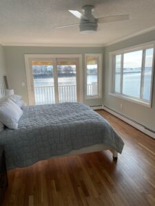 A bedroom with a large bed and a window overlooking the water.