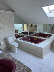 A bathroom with a toilet, tub and mirror.