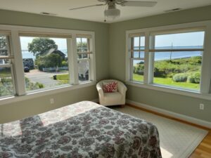 A bedroom with a view of the ocean and trees.