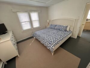 A bedroom with a bed and two windows.