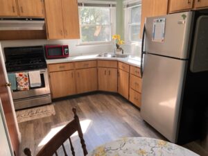 A kitchen with wooden cabinets and floors, and stainless steel appliances.