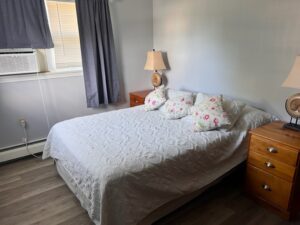 A bed room with a white bedspread and pillows