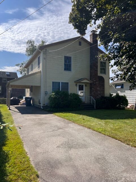 A house with a driveway and lawn in front of it.