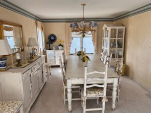 A dining room with white furniture and beige walls.