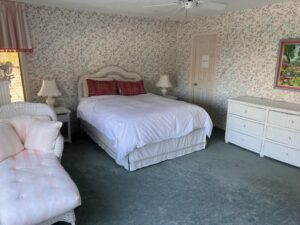 A bedroom with a bed, dresser and nightstand.