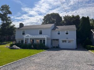 A white house with a driveway in front of it.