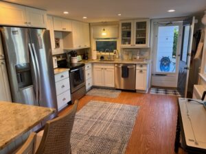 A kitchen with white cabinets and wood floors.