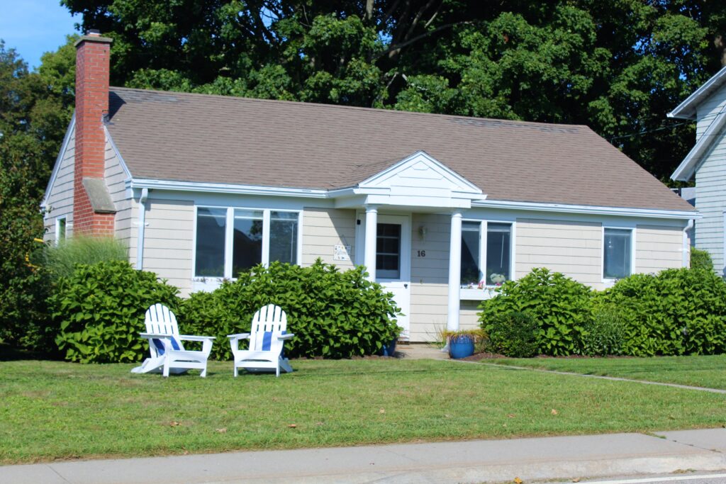 A house with two lawn chairs sitting in front of it.