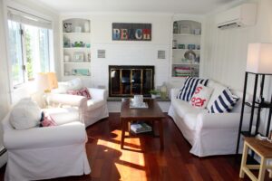 A living room with white furniture and wood floors.