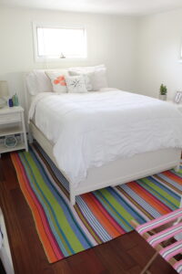 A bedroom with a bed and nightstand on the floor.