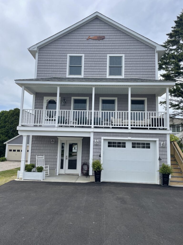 A large house with two cars parked in front of it.