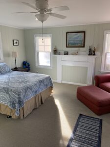 A bedroom with a bed, chair and fireplace.