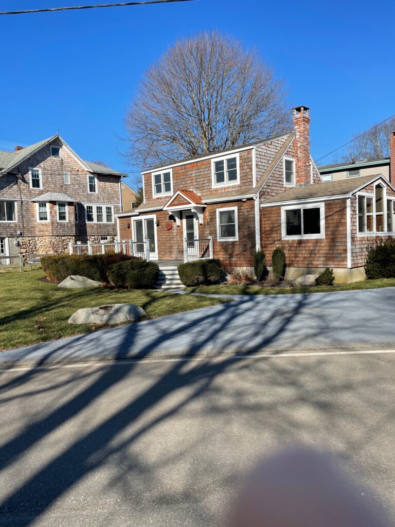 A house with trees in front of it and a driveway.