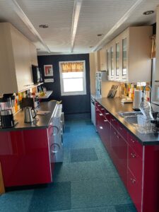 A kitchen with red cabinets and black counters.