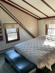 A bed room with a white bed and two windows