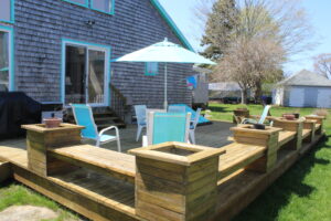 A deck with blue chairs and an umbrella.