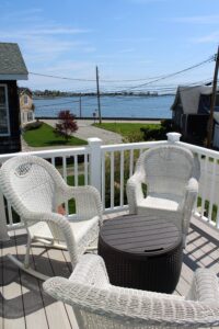 A deck with chairs and tables overlooking the water.