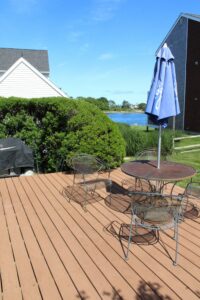 A patio with table and chairs, umbrella and lawn chair.