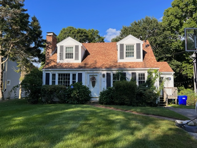 A house with a large yard and trees in the background.