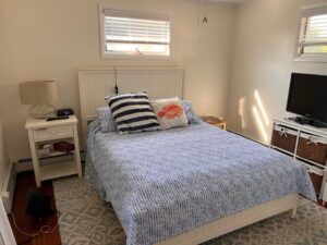 A bedroom with a bed, nightstand and window.