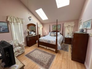 A bedroom with a bed, dresser and tv.