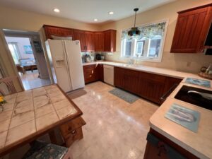 A kitchen with tile floors and wooden cabinets.