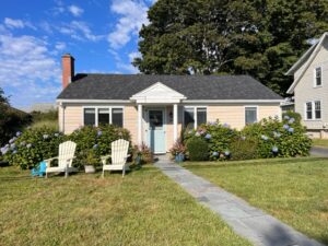 A house with two lawn chairs sitting in front of it.