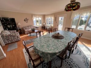 A dining room table with chairs and a couch in the background.